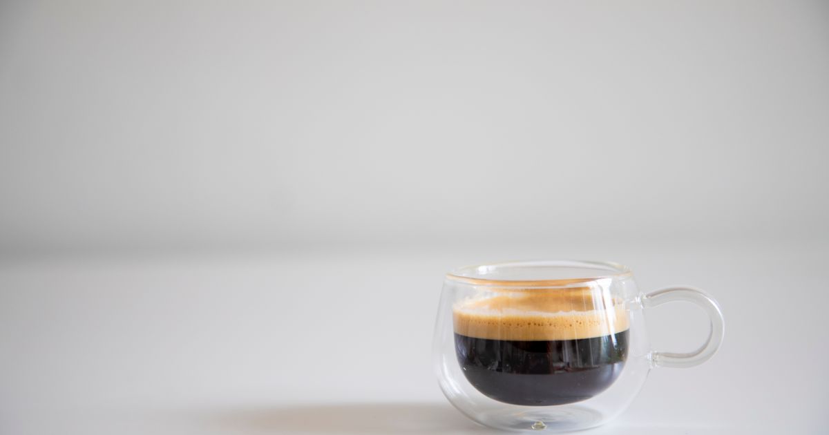 A shot of espresso with crema in a glass cup