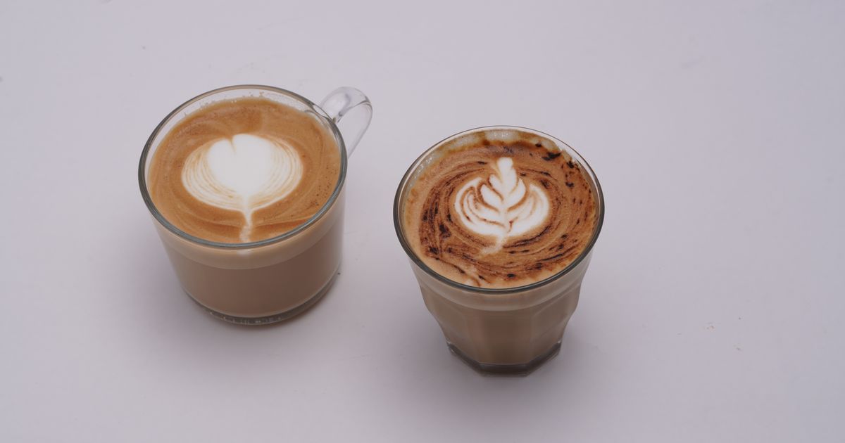 Two milky coffees with latte art in glass cups